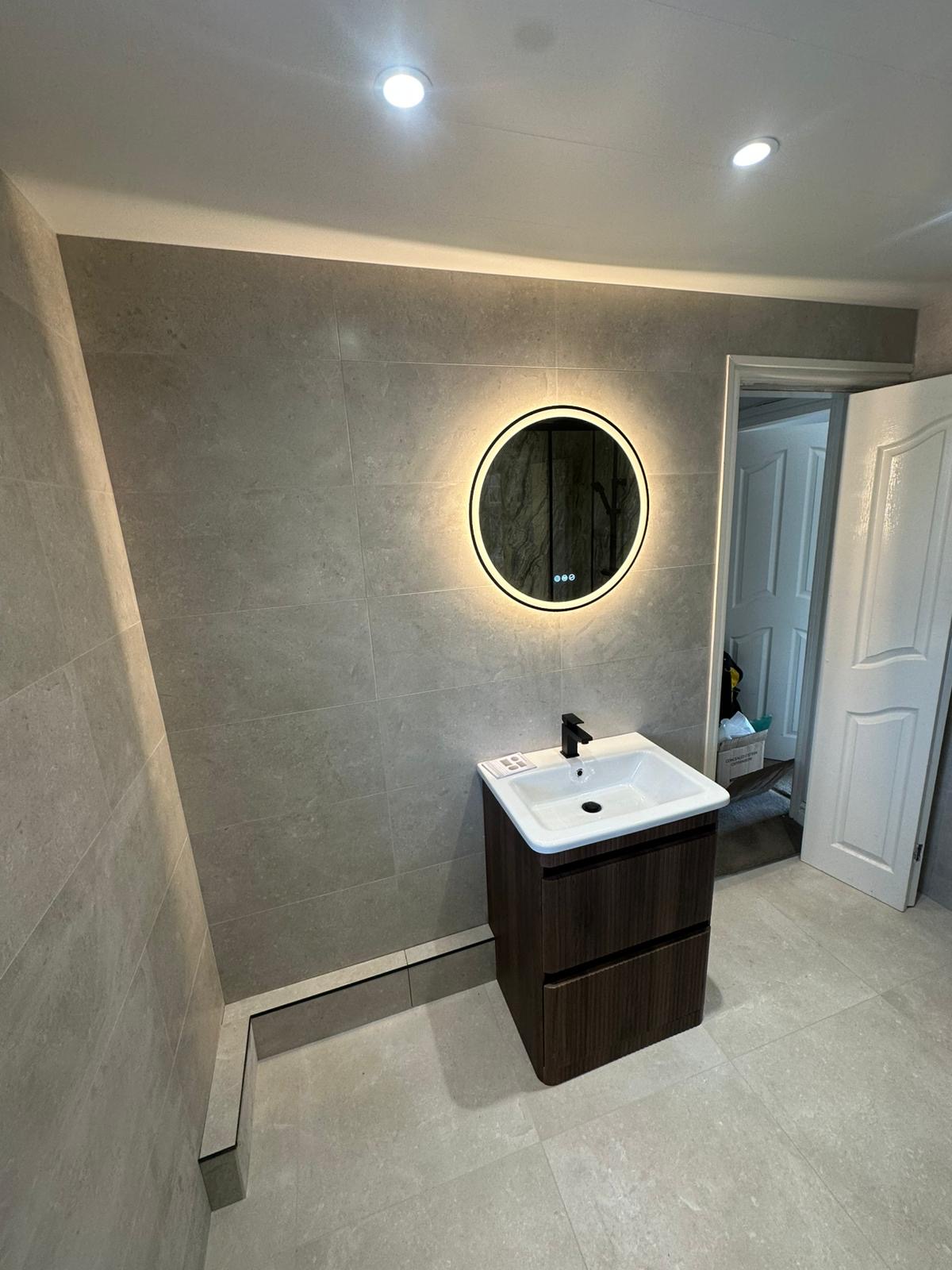 Backlit round mirror over walnut vanity
